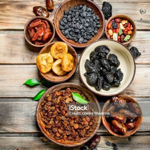 Assortment of different dried fruits in bowls. On a Wooden background.